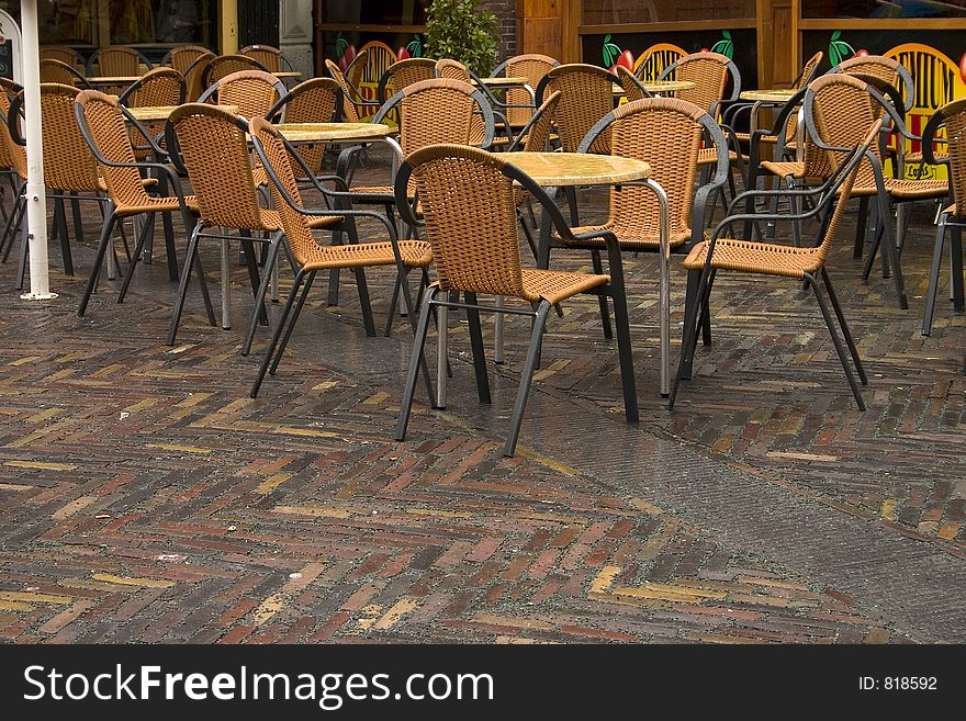 A group of wet restaurant chairs sit unoccupied. A group of wet restaurant chairs sit unoccupied