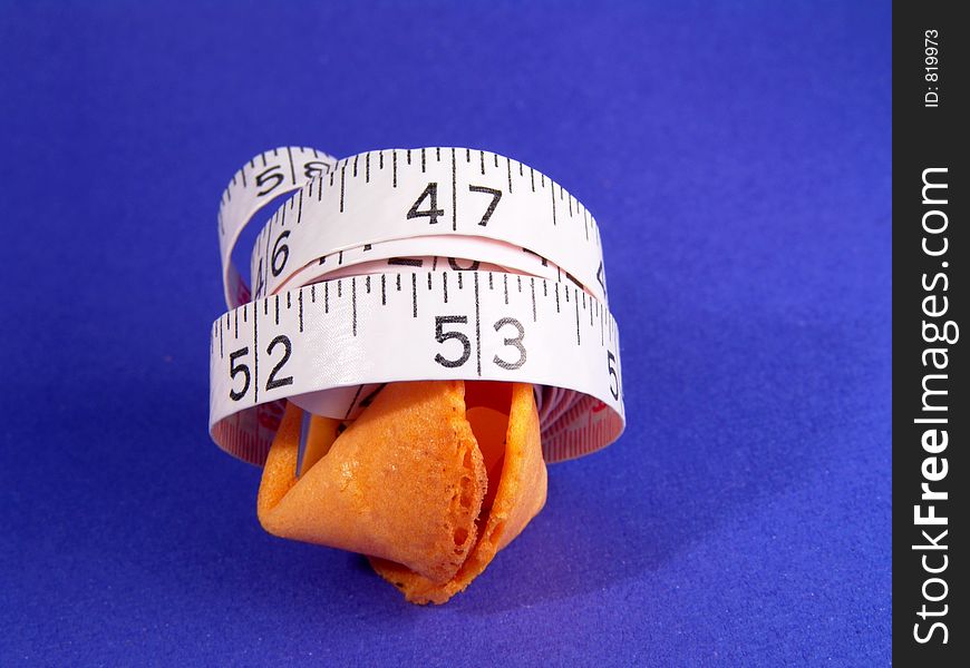 Measure tape wraps around a fortune cookie -- measuring fortune. Measure tape wraps around a fortune cookie -- measuring fortune