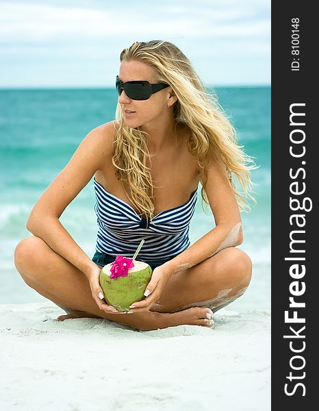 Cute girl with coconut sitting on the sand. Cute girl with coconut sitting on the sand