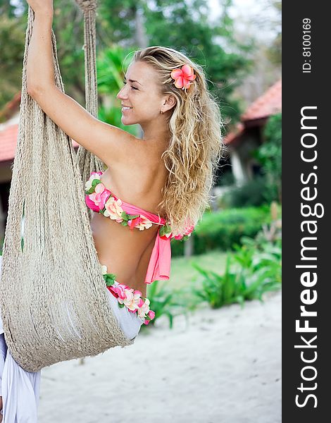 Blond girl sitting in hammock on sandy beach. Blond girl sitting in hammock on sandy beach