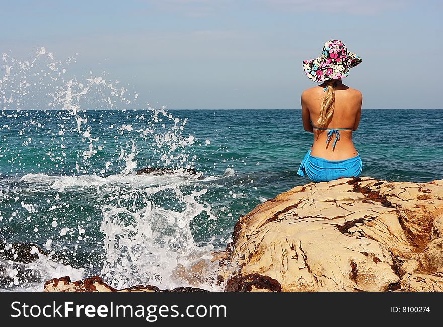 Girl sitting on rocky beach and wearing a hat. Girl sitting on rocky beach and wearing a hat