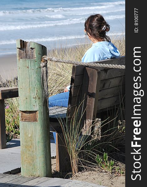 Lady sitting on a bench by the ocean. Lady sitting on a bench by the ocean