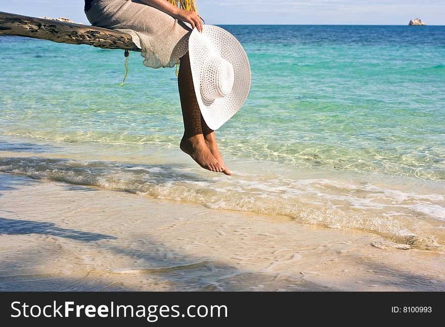 Girl sitting on the beach tree overwhelming the waters. Girl sitting on the beach tree overwhelming the waters