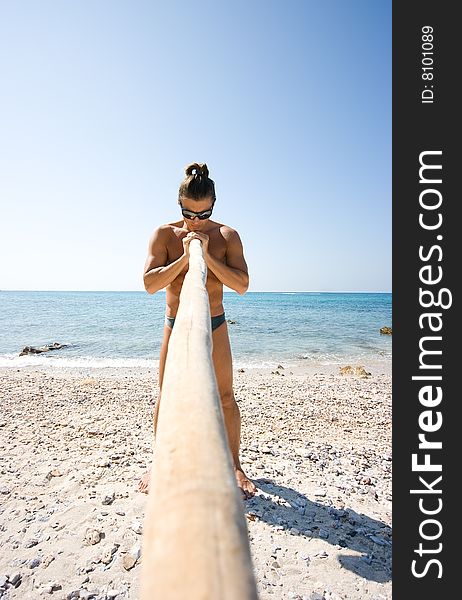 Young man standing with bamboo stick on the beach. Young man standing with bamboo stick on the beach