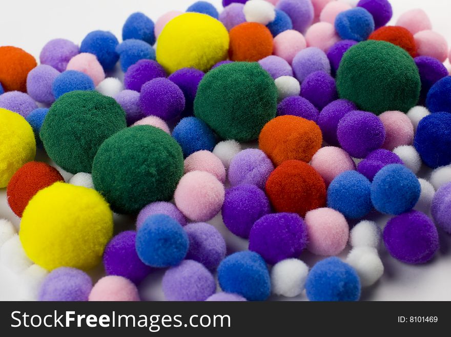 A pile of many colorful knobs - pompoms of fleece in yellow, green, blue, red and purple. A pile of many colorful knobs - pompoms of fleece in yellow, green, blue, red and purple.