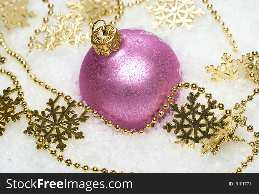 Pink festive decoration on snow with snowflakes