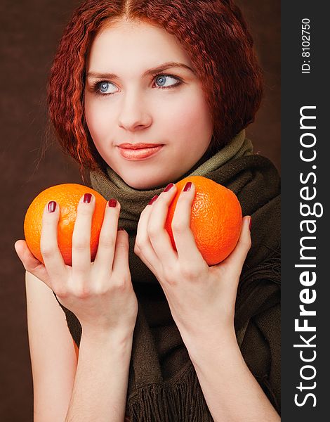 Young pretty girl with two oranges on dark background