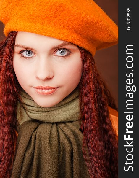 Young beautiful girl in orange beret on dark background. Young beautiful girl in orange beret on dark background