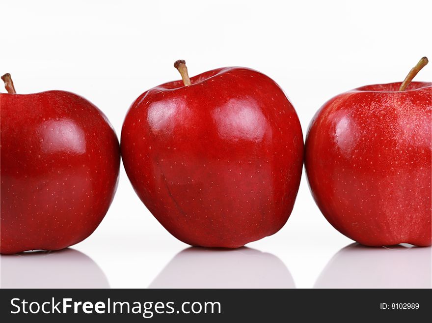 Three shiny red apples in a row isolated on white