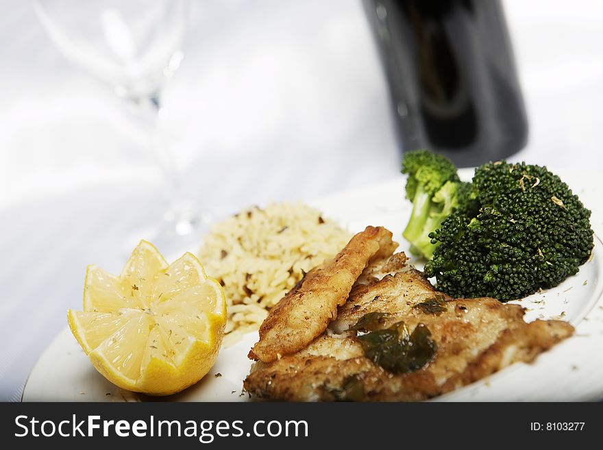 Fish meal with selective focus and wine bootle and glass in the background. Fish meal with selective focus and wine bootle and glass in the background