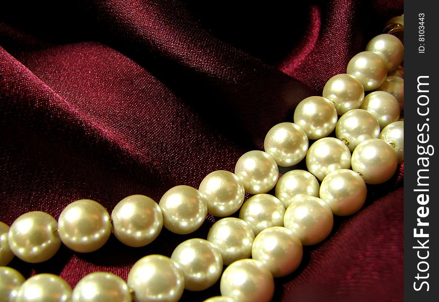 Macro photo of three Strings of pearls with a red.burgundy raw silk background. Macro photo of three Strings of pearls with a red.burgundy raw silk background