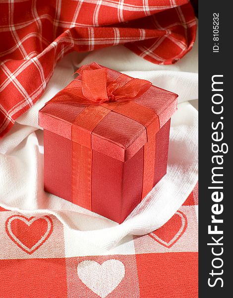 Red Valentines gift box on table cloth with red hearts. Red Valentines gift box on table cloth with red hearts