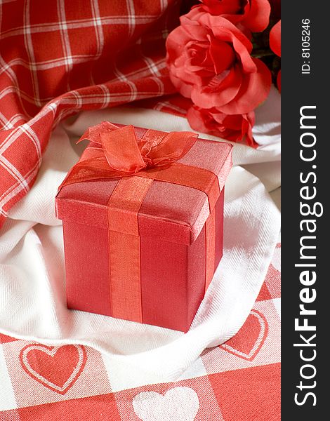 Red Valentines gift box on table cloth with red hearts. Red Valentines gift box on table cloth with red hearts