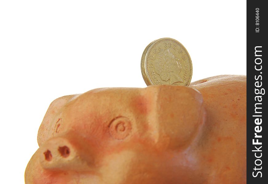 UK pound coin resting on terracotta piggy bank. UK pound coin resting on terracotta piggy bank