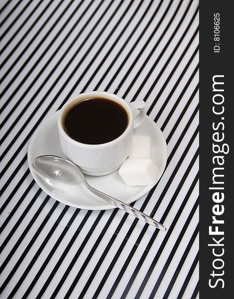 Coffee cup, the sugar and the spoon on the striped surface. Coffee cup, the sugar and the spoon on the striped surface