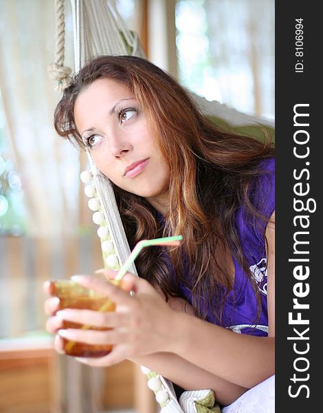 Happy long-haired girl drinking lemonade in comfortable cottage