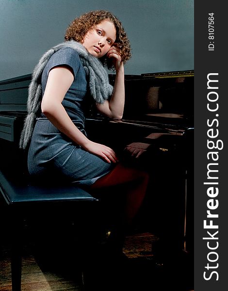 Cute dark haired lady sitting near piano