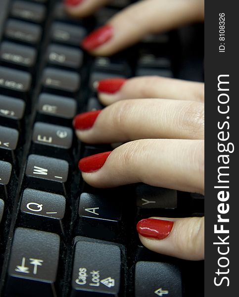 Computer keyboard and woman`s hands typing on it.