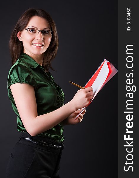 Cheerful young business woman with a red folder against a dark background