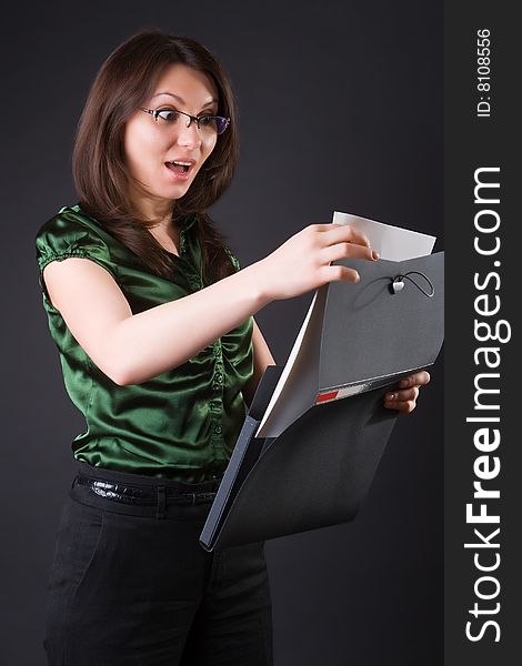 Surprised business woman with a black folder against a dark background