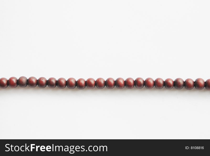 A string of wood Buddhist praying beads on the white background. A string of wood Buddhist praying beads on the white background.