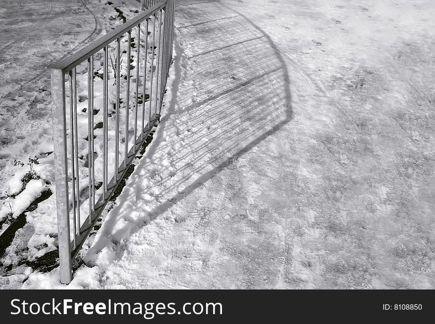 Long railing shadows across compacted snow