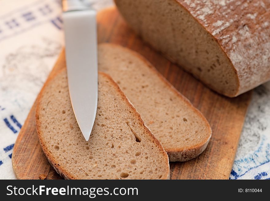 Pieces of bread on breadboard with knife. Close-up