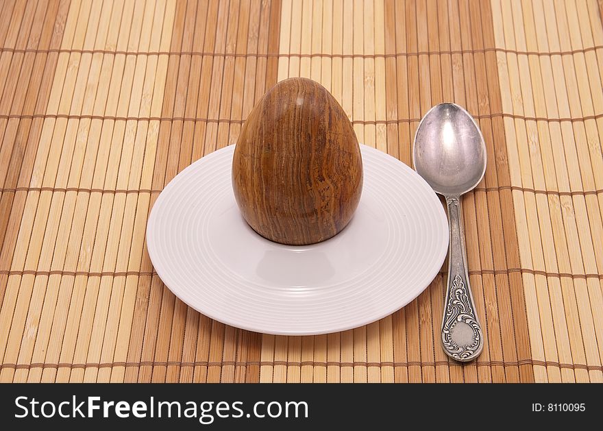 Served stone egg in a rest under egg with spoon. Close-up.