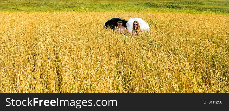 Hot summer. Two people under umbrella on the field