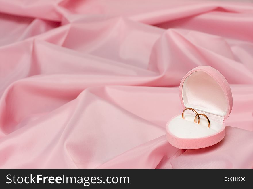 Wedding rings on background of the pink silk.