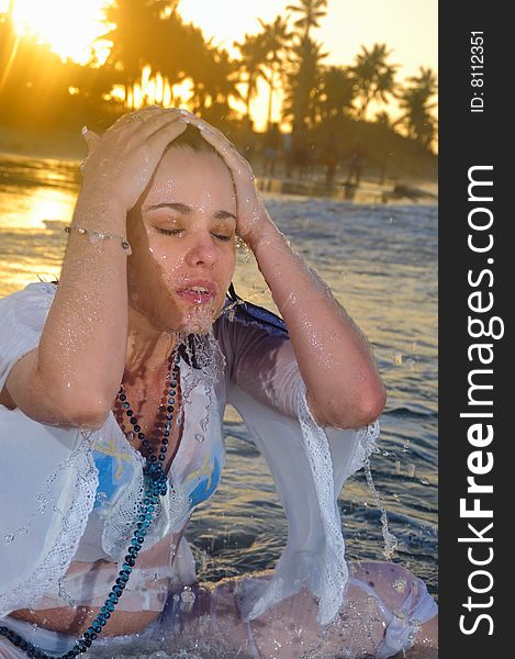 Portrait of young wet woman on the beach at sunset