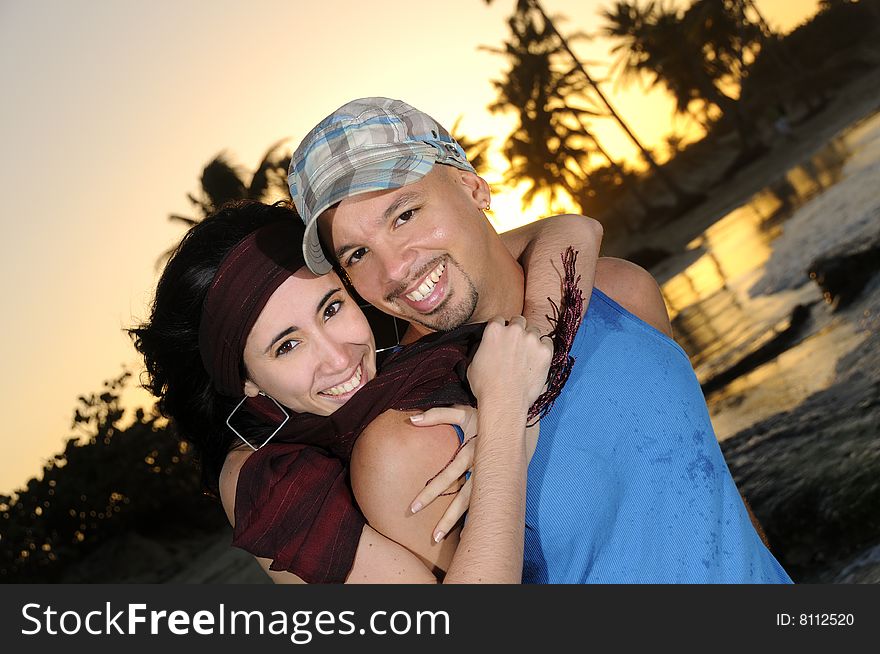 Portrait of young happy couople hugging on tropical beach at sunset. Portrait of young happy couople hugging on tropical beach at sunset