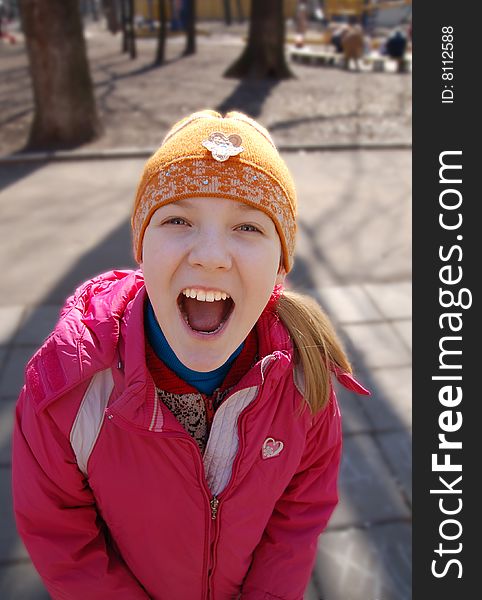 A girl in a pink jacket widely smiles in a lens. A girl in a pink jacket widely smiles in a lens