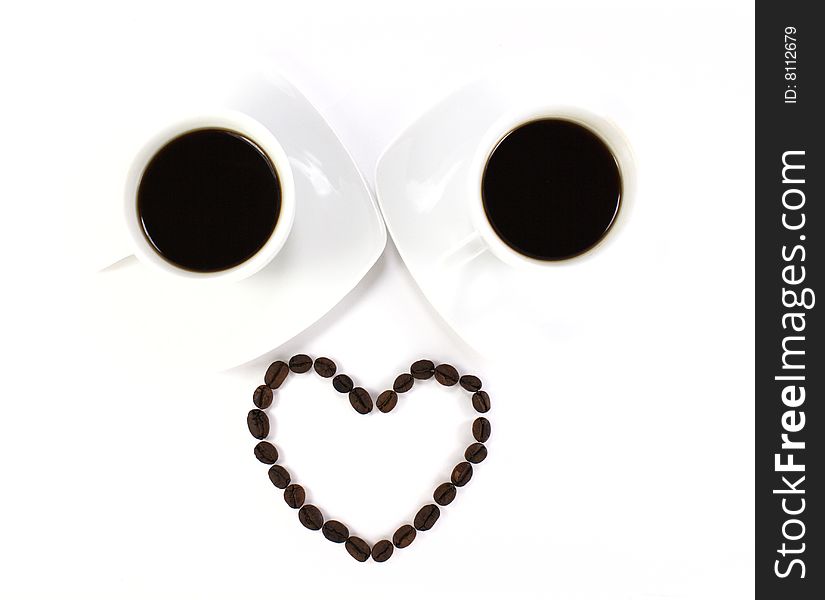 Heart made of coffee beans and two cup of coffee isolated at the white background