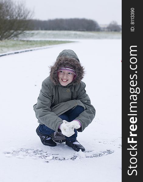 Young mischievous looking girl making a snowball