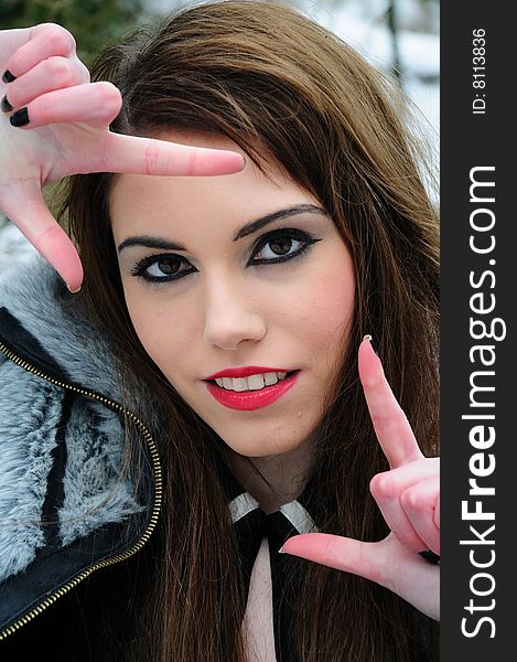 Female model holding up her finger in a L shape to capture a frame through her view. Female model holding up her finger in a L shape to capture a frame through her view