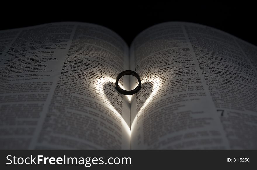 Wooden Ring on Bible with Heart Spotlight. Wooden Ring on Bible with Heart Spotlight