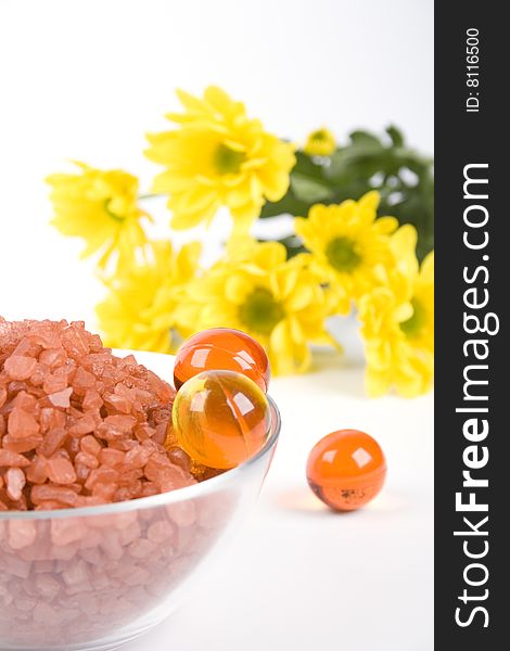 Spa pruducts: bath salt, oil balls in a bowl and yellow flowers