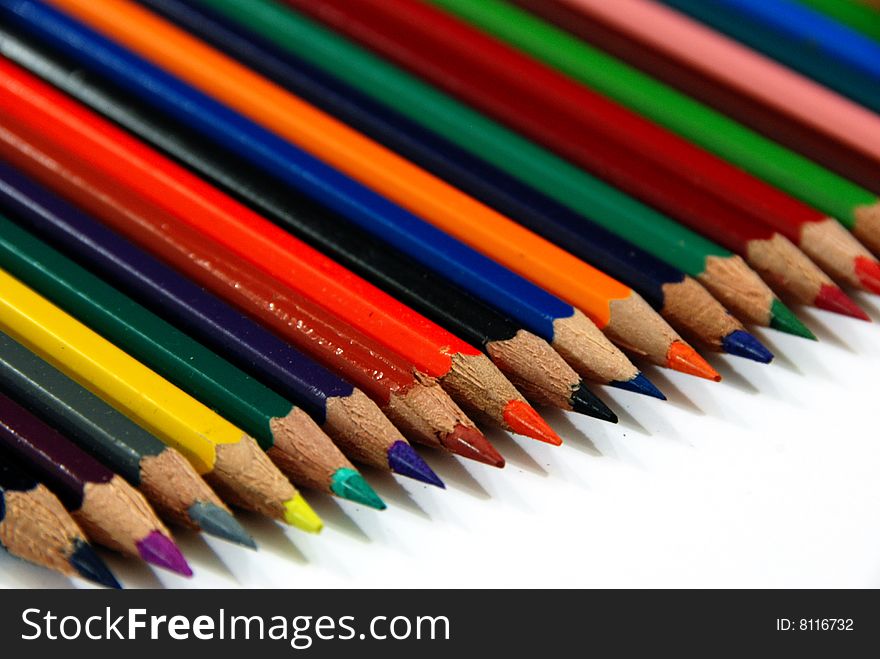 Colourful pencils line up over white