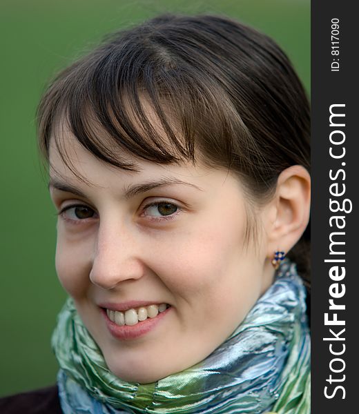 Face portrait of pretty smiling girl on green blurry background