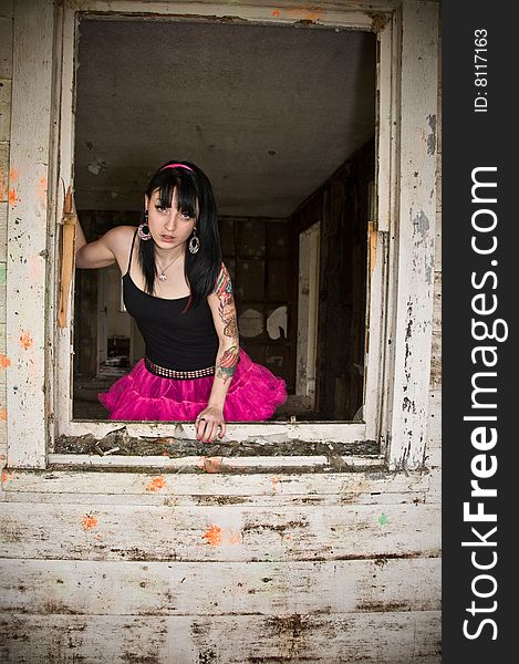 Pretty young woman standing by a window in an abandoned building