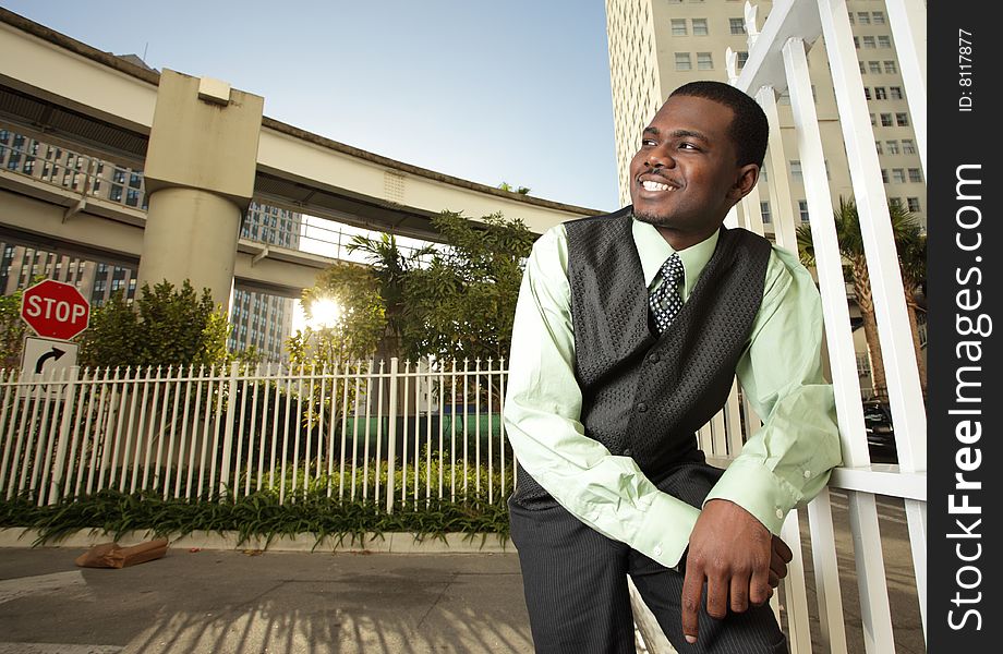 Man in a urban setting smiling while leaning on a fence. Man in a urban setting smiling while leaning on a fence