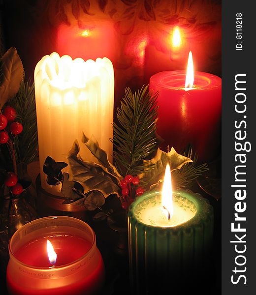 Lighted Christmas candle pillars and in jars with holly. Lighted Christmas candle pillars and in jars with holly