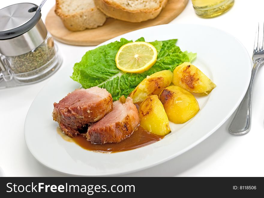 Roasted Slices Of Pork With Lettuce And Fried Potatoes.