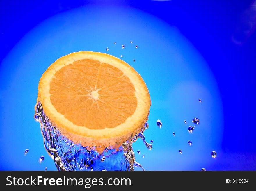 Close up view of sliced orange piece getting splashed with water. Close up view of sliced orange piece getting splashed with water