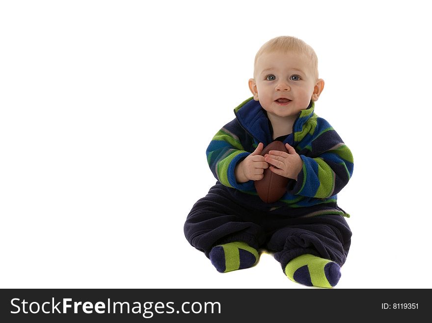 Happily teething baby boy holds football while laughing and smiling. Happily teething baby boy holds football while laughing and smiling