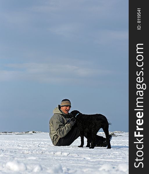 A Portuguese Water Dog retrieves a frisbee for his owner on the frozen shore of Georgian Bay, Ontario. A Portuguese Water Dog retrieves a frisbee for his owner on the frozen shore of Georgian Bay, Ontario