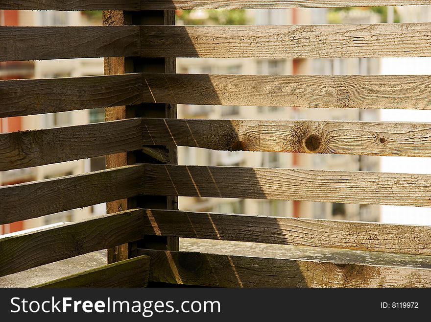 A picture of wood bars of balcony with shadows in the sun