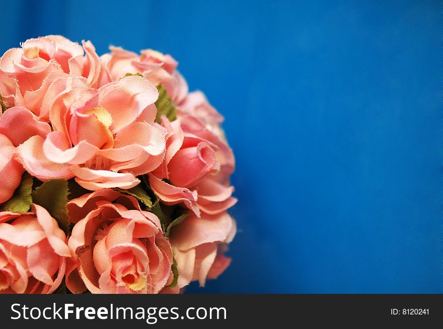 Fake pink flowers against blue background with a space for a text. Fake pink flowers against blue background with a space for a text