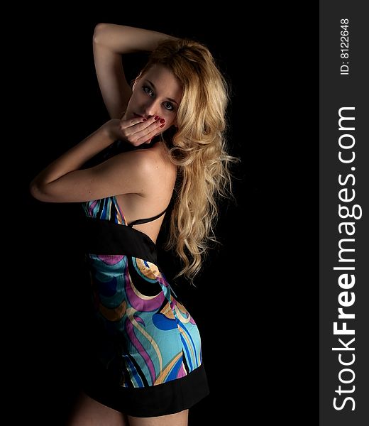 Beautiful blonde young lady in multicolored dress on black background